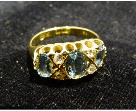 An 18ct Yellow Gold Aquamarine and Diamond Ring set with three aquamarines interspaced by diamonds within a pierced setting