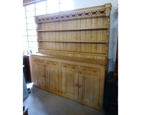 A Large Pine Dresser, the boarded shelf back with a pierced frieze and eight spice drawers, the lower section with four drawe