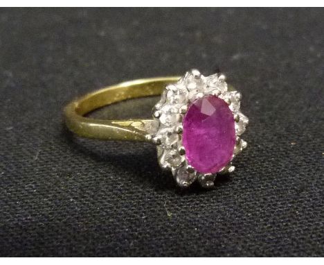 An 18ct. Gold Ruby and Diamond Cluster Ring, set with a central oval ruby surrounded by diamonds within a pierced setting