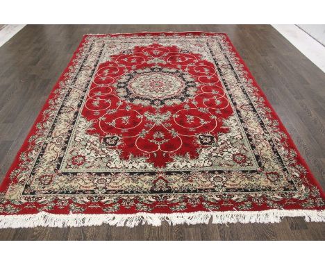 A North West Persian Woollen Carpet with a central medallion within an all-over design upon a red and beige ground within mul