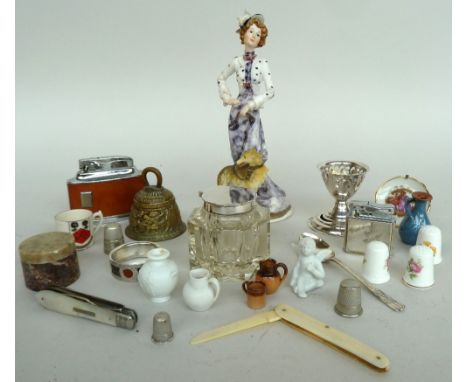 A mixed lot containing several ceramic thimbles, two lighters, an inkwell and a resin figurine of a lady with a dog, amongst 