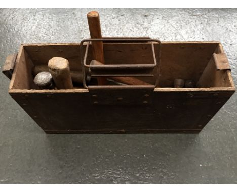A wooden ammo box filled with various vintage tools including small hammers and stone chisels 