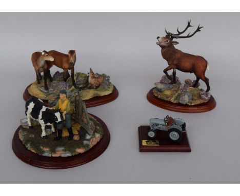 Three resin figurines depicting a stag, a doe with two fawns and a farmer milking a cow together with a model of a TE20 tract