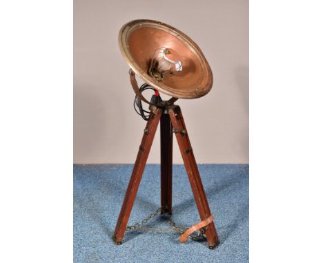 A VINTAGE INDUSTRIAL CONVERTED HEAT LAMP, the light fitting within a coppered shade, on a wooden tripod stand, minimum height