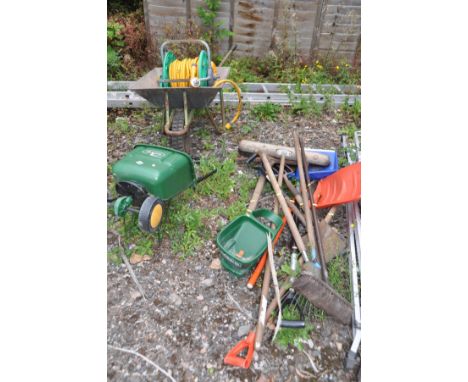 A QUANTITY OF GARDEN TOOLS AND A WHEELBARROW including spades, rakes, seed spreaders, hosepipe on reels etc