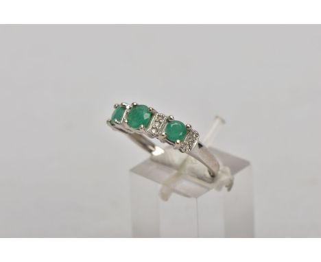 A 14CT WHITE GOLD EMERALD AND DIAMOND RING, designed with three circular cut emeralds, interspaced with round brilliant cut d