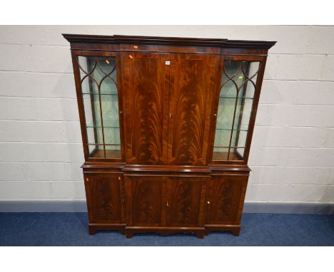 A REPRODUDUCTION MAHOGANY BREAKFRONT BOOKCASE/COCKTAIL CABINET, the top section with two glazed doors flanking double cupboar