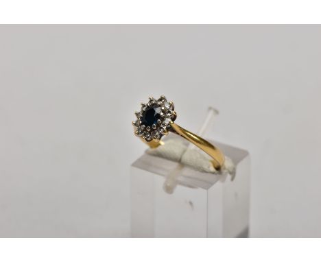 AN 18CT GOLD SAPPHIRE AND DIAMOND CLUSTER RING, centring on an oval cut blue sapphire, within a surround of round brilliant c