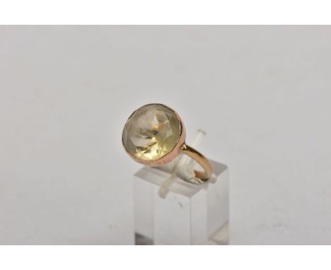 A YELLOW METAL CITRINE DRESS RING, set with a circular cut citrine within a collet mount, plain polished band, no hallmark or