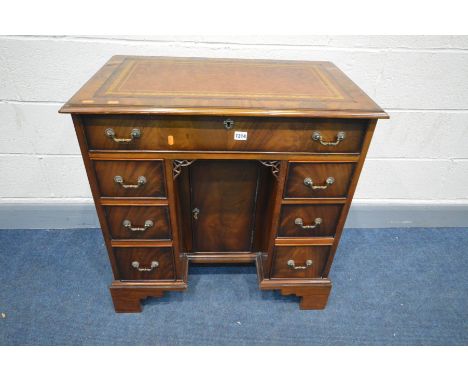 A GOOD REPRODUCTION SLIM MAHOGANY KNEE HOLE DESK, brown and gilt tooled inlay top, seven drawers and single cupboard doors, o