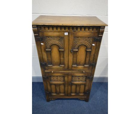 A REPRODUCTION OAK FOUR DOOR DRINKS CABINET, the arched panel door enclosing an arched shelf, and a brushing slide, width 76c