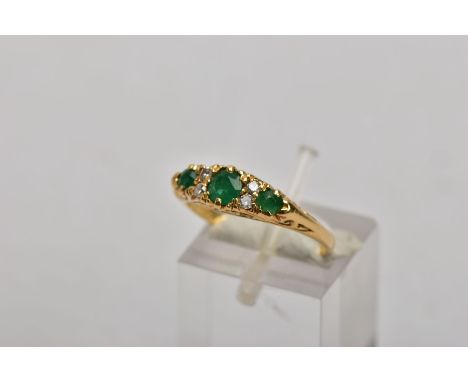 A YELLOW METAL, EMERALD AND DIAMOND RING, designed with a central circular cut emerald, flanked with round brilliant cut diam