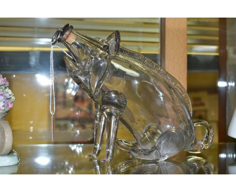 A NOVELTY GLASS DECANTER IN THE OF A SEATED PIG OR GIN PIG, free blown form with cork and metal stopper, height 21cm x 18cm