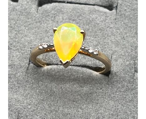 10ct yellow gold ring set with a pear cut Ethiopian opal stone flanked by white topaz stone shoulders. [Ring size P] [2.33Gra