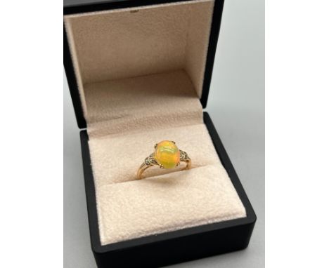 10ct yellow gold ring set with an Ethiopian opal cabochon stone flanked by green spinel stones. [Ring size Q] [2.39Grams] 