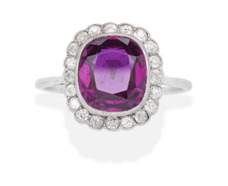 RUBY AND DIAMOND CLUSTER RING, EARLY 20TH CENTURYThe cushion-shaped ruby within a cushion-shaped diamond surround, ruby appro