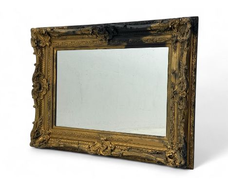 Victorian design giltwood wall mirror, richly carved with scrolls, shells, and foliate motifs, rectangular plate set within a