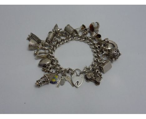 A VINTAGE SILVER CHARM BRACELET, comprising of twenty four novelty charms to the heart shape padlock, hallmarks for London