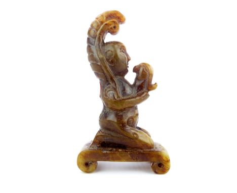 A Chinese small carved brown and green jade kneeling figure holding a bird, 8cm high.