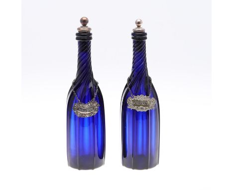 A pair of blue glass decanters with fluted bodies, one with a silver and cork stopper, the other silver plated and cork, and 