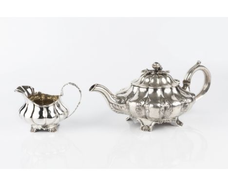 A WILLIAM IV SILVER TEAPOT of lobed and compressed form, the lobes with stylized leaf decoration, and having rose finial, on 