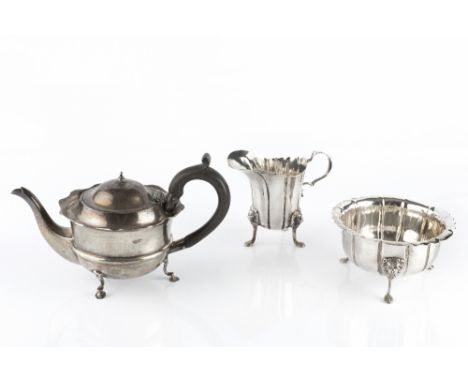 AN EDWARDIAN SILVER MILK JUG AND MATCHING SUGAR BASIN, of shaped and panelled form, on lion's mask paw feet, by Williams Ltd,