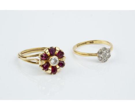 A RUBY AND DIAMOND CLUSTER RING, modelled as a stylized flowerhead, the central round brilliant-cut diamond collet set within