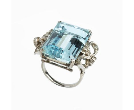 AN AQUAMARINE AND DIAMOND COCKTAIL RING, the rectangular step-cut aquamarine in double claw setting, between openwork ribbon 