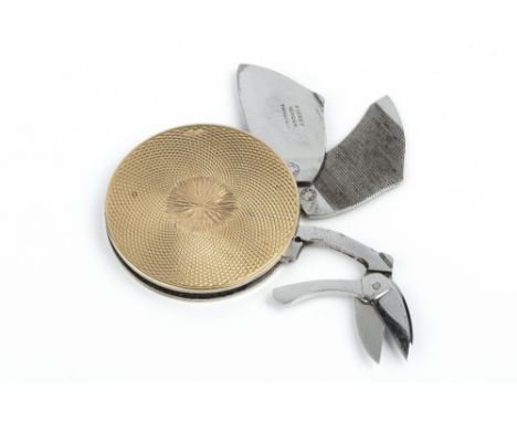 A 9CT GOLD CIRCULAR MANICURE TOOL, by Asprey & Co. Ltd, with engine turned decoration, fitted with steel scissors, blade and 