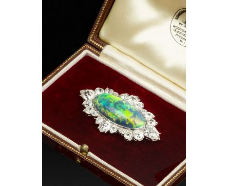 A BLACK OPAL AND DIAMOND CLUSTER PANEL BROOCH, the oval cabochon black opal collet set within a foliate border of graduated p