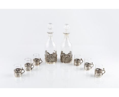 A LATE VICTORIAN SILVER MOUNTED GLASS LIQUEUR SET, comprising two wrythen decanters and stoppers, the silver mounts pierced a