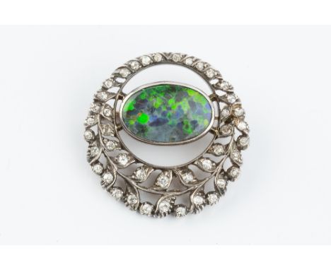 A DIAMOND SET PANEL BROOCH, the openwork foliate panel of graduated old and single-cut diamonds enclosing an oval opalescent 