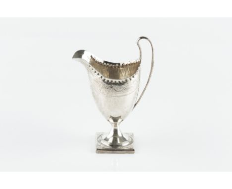 A GEORGE III SILVER HELMET SHAPED CREAM JUG, with punched border and bright cut decoration, on square pedestal foot, visible 