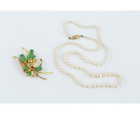 A JADE SPRAY BROOCH, modelled as a pierced and scrolled ribbon with a spray of oval and pear-shaped jade cabochons, stamped '