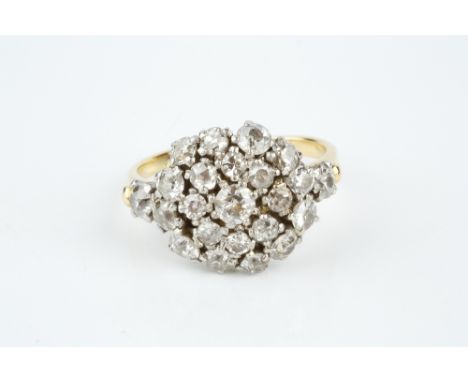 A DIAMOND CLUSTER RING, the circular target cluster of graduated old and single-cut diamonds in claw settings, between simila