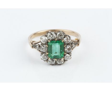 AN EMERALD AND DIAMOND CLUSTER RING, the rectangular step-cut emerald claw set within a border of old-cut diamonds, between p