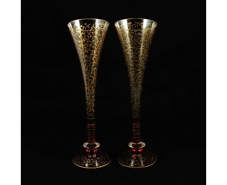 Set of fifteen Murano glass flutes, clear glass with ruby bases, scrolled gilt design, each 28cm.