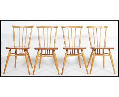 A set of 4 mid century retro Ercol dining chairs being raised on turned legs with stretchers, saddle seats and with spindle g