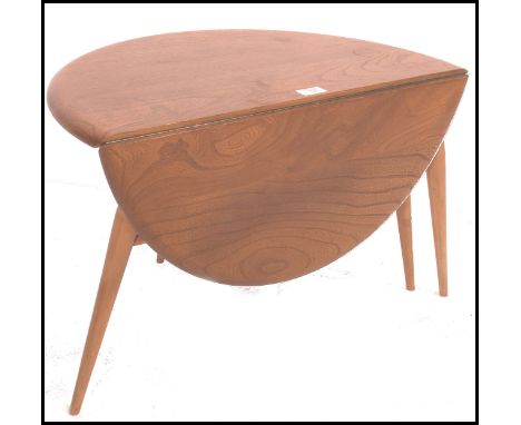 An Ercol retro 1970's drop leaf circular coffee - occasional table by Ercol raised on tapered legs with chamfered edge table 