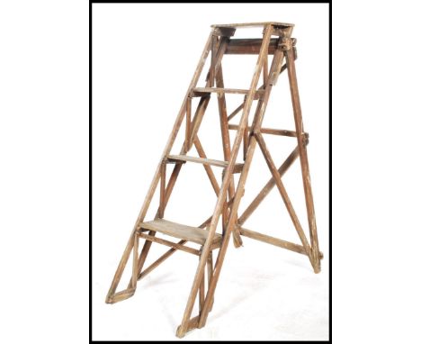 An early 20th century wooden Industrial step ladder with trellis worked sides having a-frame folding action