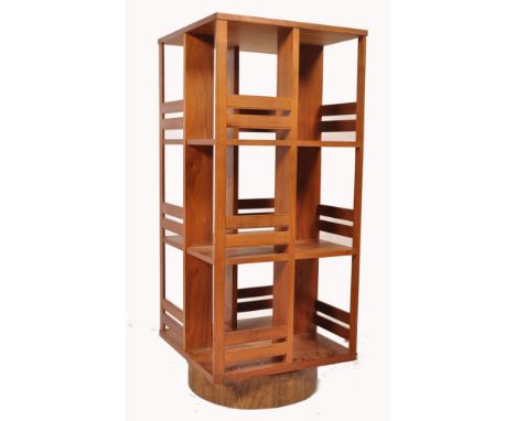 An unusual mid century teak wood revolving bookcase of large upright form with slatted body raised over a trunk plinth wooden