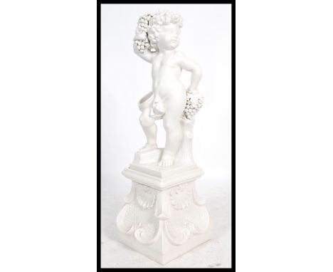 A large floor standing ceramic statue of a cherub / putti holding a bunch of grapes. Set over a large white glaze plinth base