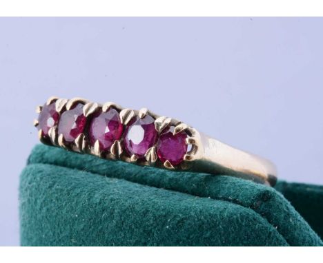 A yellow metal five stone ruby dress ring, in claw setting, the oval mixed cut rubies in double claws, ring size R, 2.6g