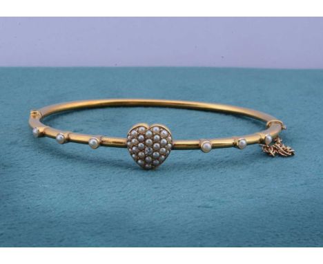 An Edwardian seed pearl and diamond hinged bangle, the central heart encrusted with half cut pearls centred with small old cu