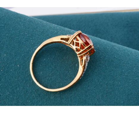 An 18ct gold Lorique garnet and diamond set dress ring, the oval mixed cut tangerine garnet in four claw setting with ornate 