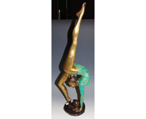 An Art Deco style bronze figure, as a ballet dancing girl with ball, green and gilt painted costume, shaped base, 54cm high