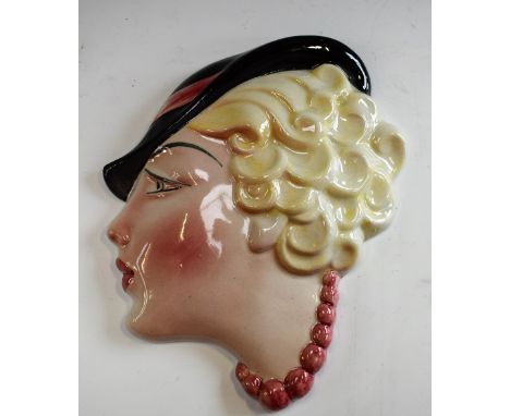 An Art Deco Staffordshire wall mask, as a lady of fashion with curling blonde bobbed hair in cloche hat and pink bead necklac