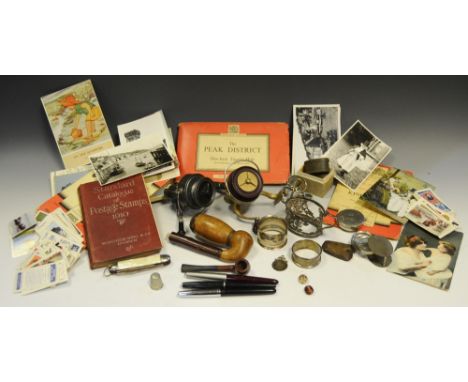 A fishing reel, KP Morritt, pat.no. 798024; another; a pipe; Ordnance Survey maps; postcards; stamps; cigarette cards; pens; 