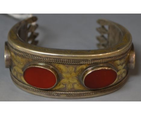 A white metal parcel gilt bangle, set with carnelians