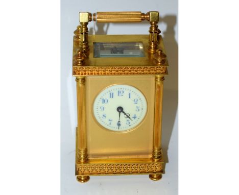 A French gilt metal carriage clock, the white dial with blue Arabic numerals, the case with wirework anthemions, swing handle